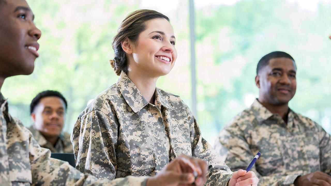 Three servicemembers listen to a lecture at a military academy